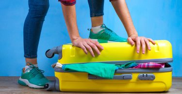 Żółta walizka pełna rzeczy - Jak się spakować na wyjazd